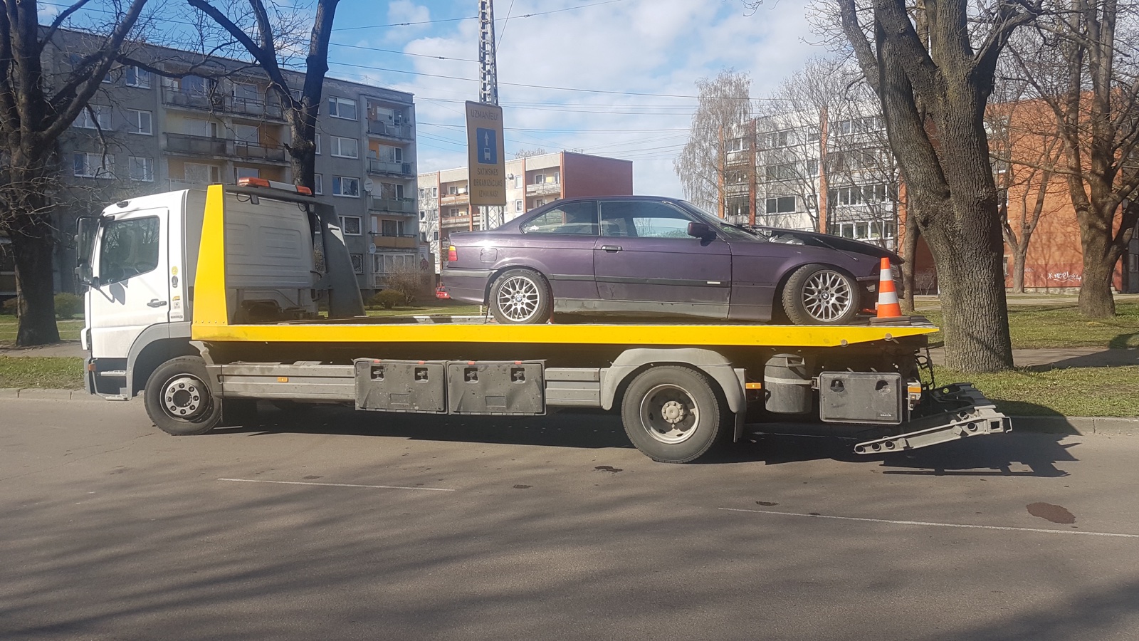 Autovadītājs pārbauda riepu spiedienu automašīnai karstā vasaras dienā uz ceļa ar manometru, nodrošinot drošību. RS Auto